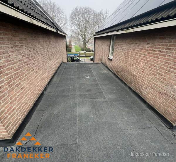 Plat dak met bitumen dakbedekking tussen bakstenen muren in Franeker Plat dak met bitumen dakbedekking tussen bakstenen muren in Franeker