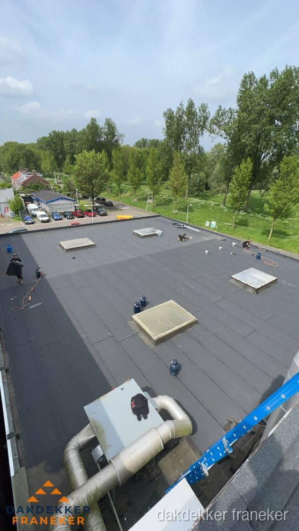 Dakdekker aan het werk op groot plat dak met bitumen in Franeker Dakdekker aan het werk op groot plat dak met bitumen in Franeker