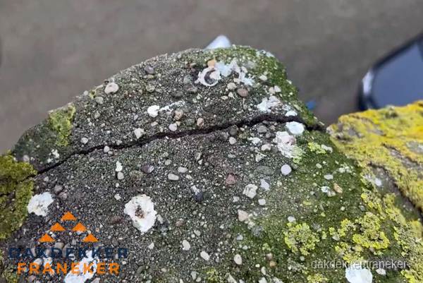Beschadigde en verweerde nokvorst met scheuren en mos in Franeker Beschadigde en verweerde nokvorst met scheuren en mos in Franeker