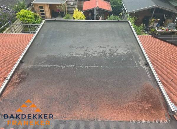 Verouderd plat dak met slijtage tussen schuine daken in Franeker Verouderd plat dak met slijtage tussen schuine daken in Franeker